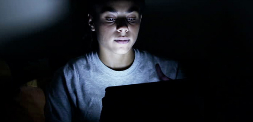 Woman looking at laptop screen in the dark