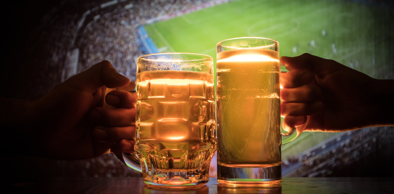 Two people clinking beer glasses against each other