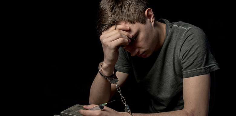 Man in handcuffs with head in hands