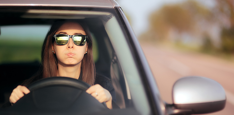 Nervous woman in sunglasses driving car