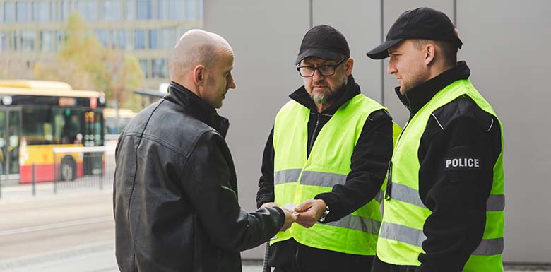 Two police officers talking to a man on the sidewalk