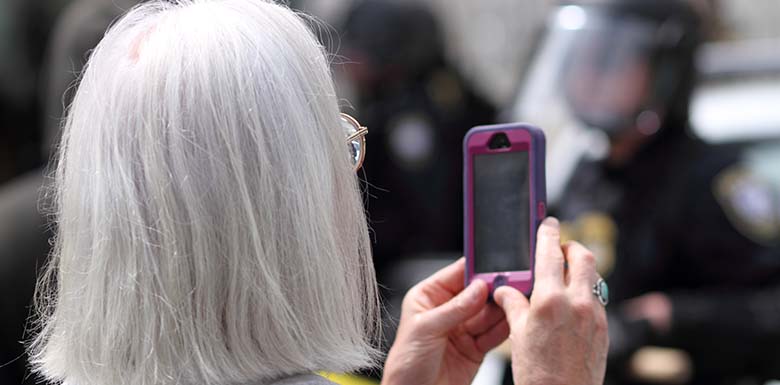 Older woman using phone to record police officers